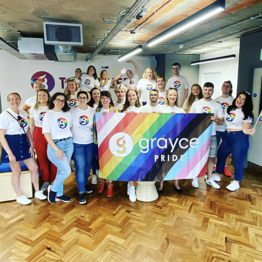 Alt='people stood with LGBTQ flag'